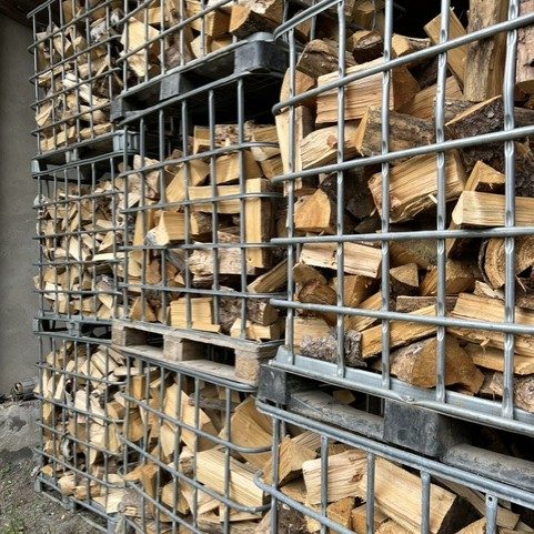 Brennholzlagerung Gestapelte Holzscheite in Drahtkörben, außen gelagert.