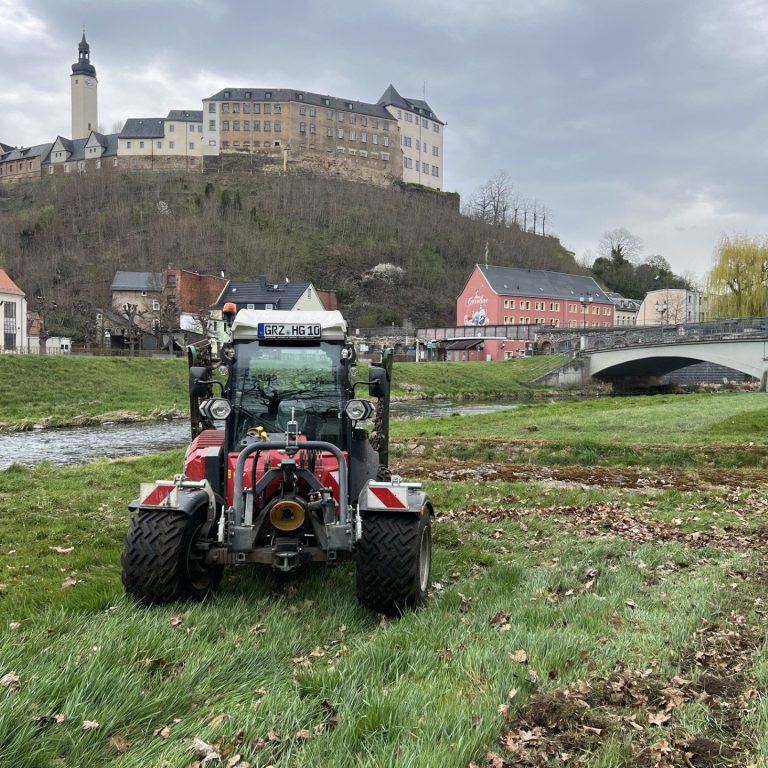 Wiese Abschleppen am Ufer der Weißen Elster in Greiz, Vogtland Ein Traktor vor einer Burg und einem Fluss in Landkreis Greiz